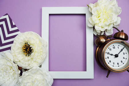 White Frame with alarm clock and flower decoration on purple backgroundの写真素材