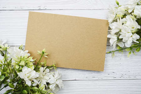 Empty paper card with white daisy flower flat lay on wooden backgroundの写真素材