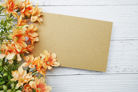 Empty paper card with orange daisy flower flat lay on wooden backgroundの写真素材
