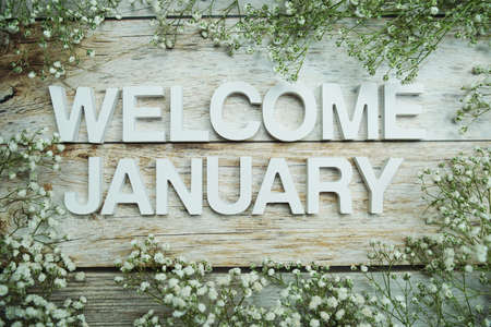 Welcome January alphabet letters with flowers on wooden backgroundの写真素材