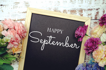 Happy September text on background decorated with flower bouquet on wooden background