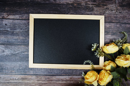 Empty Blackboard with flowers decoration on wooden backgroundの写真素材