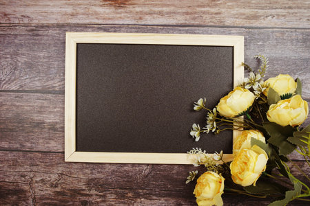 Empty Blackboard with flowers decoration on wooden backgroundの写真素材