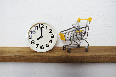White alarm clock and Yellow mini shopping trolley cart on wooden shelves