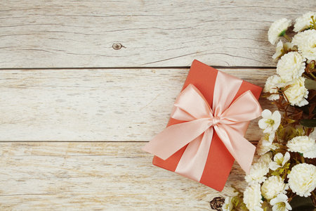 Gift box with pink ribbon with space copy on wooden background