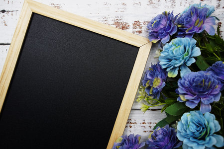 Empty blackboard with flower on wooden backgroundの写真素材