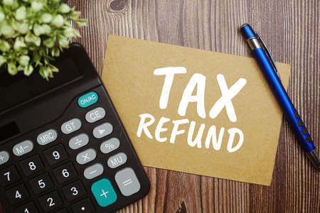 Tax Refund typography text on paper card with calculator on wooden backgroundの写真素材