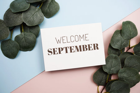 Welcome September text message with green leave on blue and pink background