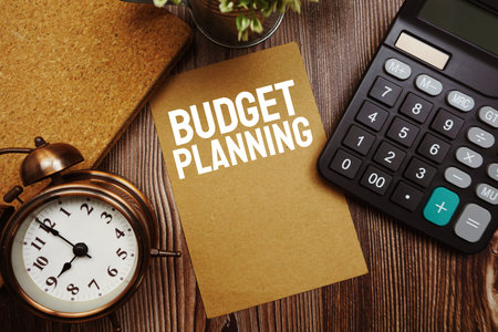Budget Planning typography text on paper card with calculator on wooden background