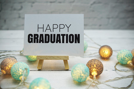 Happy Graduation text on white brick wall and wooden background
