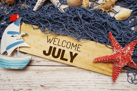 Welcome july text message decoration with seashell and marine on wooden backgroundの写真素材