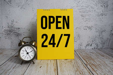 Open 24 Hrs. 7 day Service text message and alarm clock on wooden backgroundの写真素材