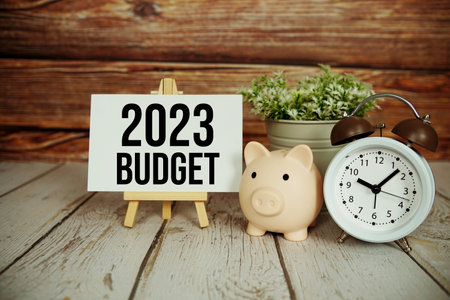 2023 Budget text message with alarm clock and piggy saving on wooden backgroundの写真素材