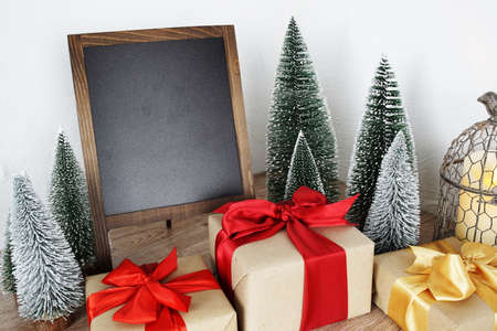 Gift boxes and Blank Blackboard wooden easel with Christmas tree and LED candle lightの写真素材