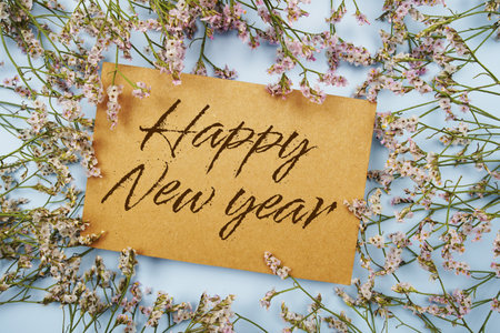 Happy New Year written on paper card with flower frame decoraton on pink backgroundの写真素材