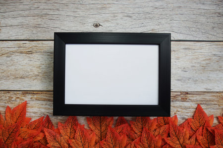 Empty mock up photo frame with maple leaves on wooden background