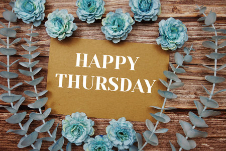 Happy Thursday typography text on paper card decorate with flower on wooden background