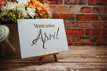 Welcome April text with flower bouquet decoration on wooden and old brick