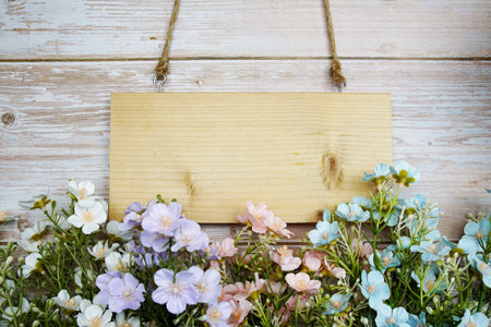 Empty space of Wooden sign hanging with rope and artificial flower decoration on wooden backgroundの写真素材