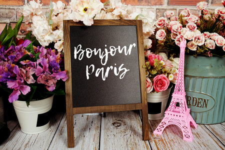 Bonjour Paris text message write on chalkboard with pink Eiffel tower souvenir and flower bloomingの写真素材