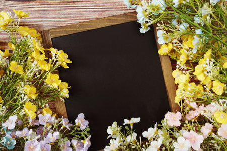 Empty Chalkboard mockup space for text message with flower decoration top view on wooden backgroundの写真素材
