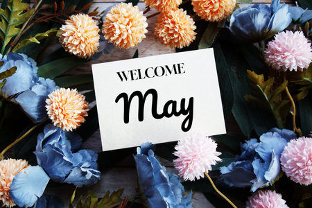 Welcome May text message with flower decoration on wooden background