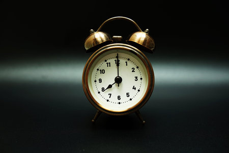 Vintage alarm clock at 8 o'clock on black background
