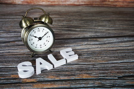 Sale alphabet letters with alarm clock on wooden backgroundの写真素材