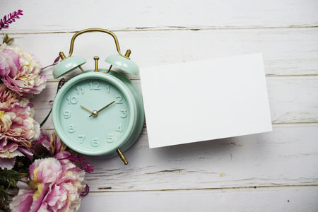 Empty card mockup with flower bouquet and alarm clock on wooden background