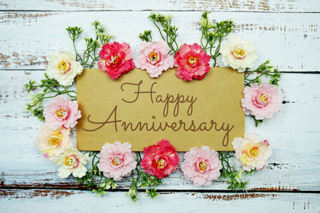 Happy Anniversary typography text decorate with flower on wooden backgroundの写真素材