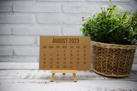 August 2023 monthly calendar with green leaf decoration on wooden background