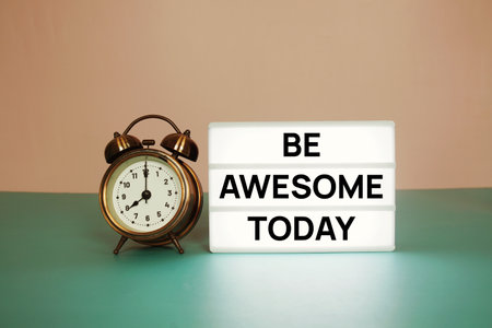 Be Awesome Today text message on paper card with wooden easel and alarm clockの写真素材