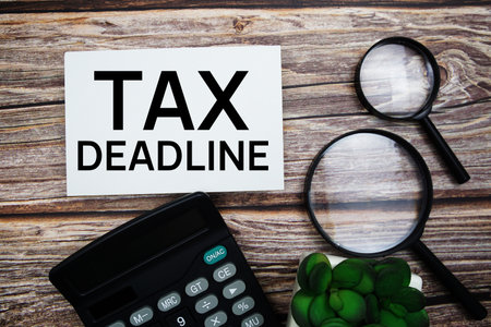 Tax Deadline text message with calculator and magnifying top view on wooden backgroundの写真素材