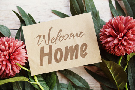 Welcome Home text message with flower decoration on wooden backgroundの写真素材