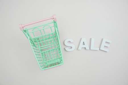 Sale alphabet letters with trolley shopping cart top view on pink backgroundの写真素材