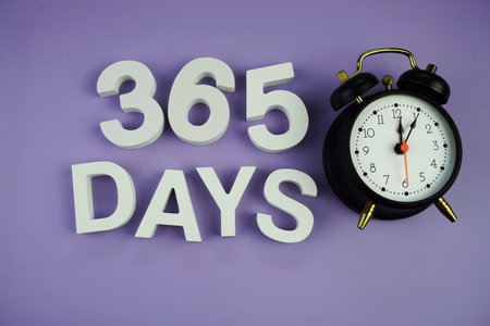 365 Days alphabet letters with alarm clock top view on purple background, business and education...