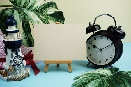 Summer background with alarm clock and light house decoration on blue and yellow background