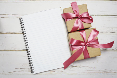 Empty Notebook and Gift boxes with pink ribbon on wooden backgroundの写真素材
