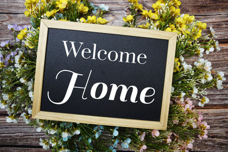 Welcome Home write on blackboard and flower decoration top view on wooden backgroundの写真素材