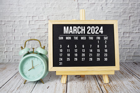 March 2024 monthly calendar and alarm clock on wooden backgroundの写真素材