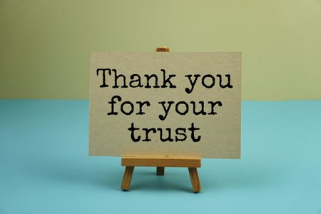Thank you for your trust text message written on paper card with alarm clock on blue and yellow...