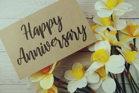 Happy Anniversary typography text on paper card decorate with flower on wooden backgroundの写真素材