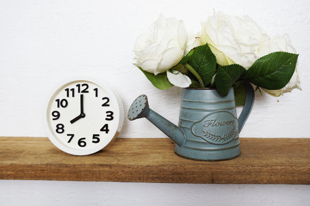 Home decoration accessories white alarm clock and Flower in metal vase  on wooden shelves and white...
