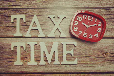 Tax Time alphabet with alarm clock on wooden backgroundの写真素材