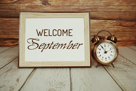 Welcome September text message with alarm clock on wooden backgroundの写真素材