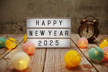 Happy New Year 2025 text on lightbox on wooden background