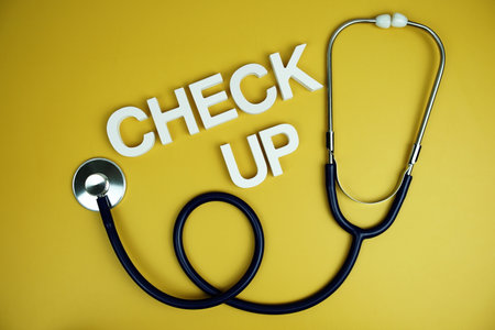 Stethoscope and Check up alphabet letters top view on yellow backgroundの写真素材