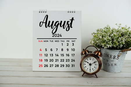 August 2024 monthly calendar with vintage alarm clock on wooden backgroundの写真素材