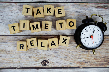 Take Time To Relax with wooden blocks alphabet letters and alarm clock on wooden backgroundの写真素材