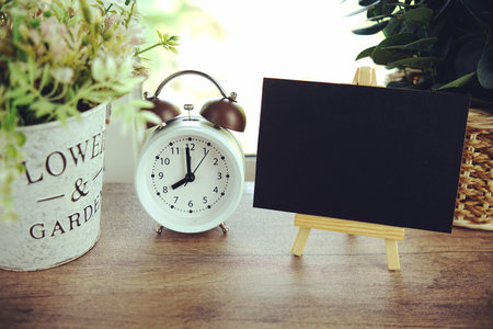 Empty card space for text message with wooden easel and alarm clcok on wooden backgroundの写真素材